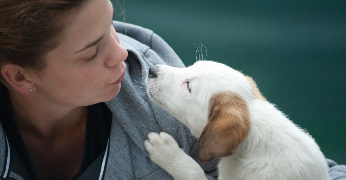 A candid shot of a woman and puppy sharing a tender moment outdoors