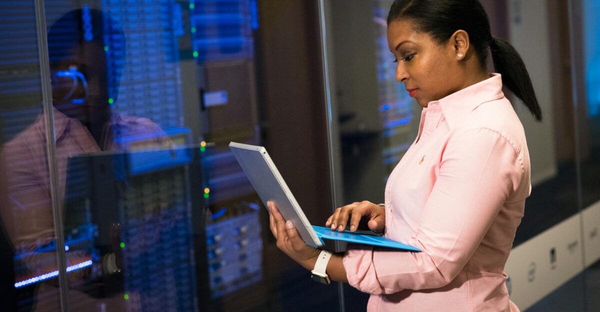 A focused software engineer working on a laptop in a server room reflecting dedication in tech