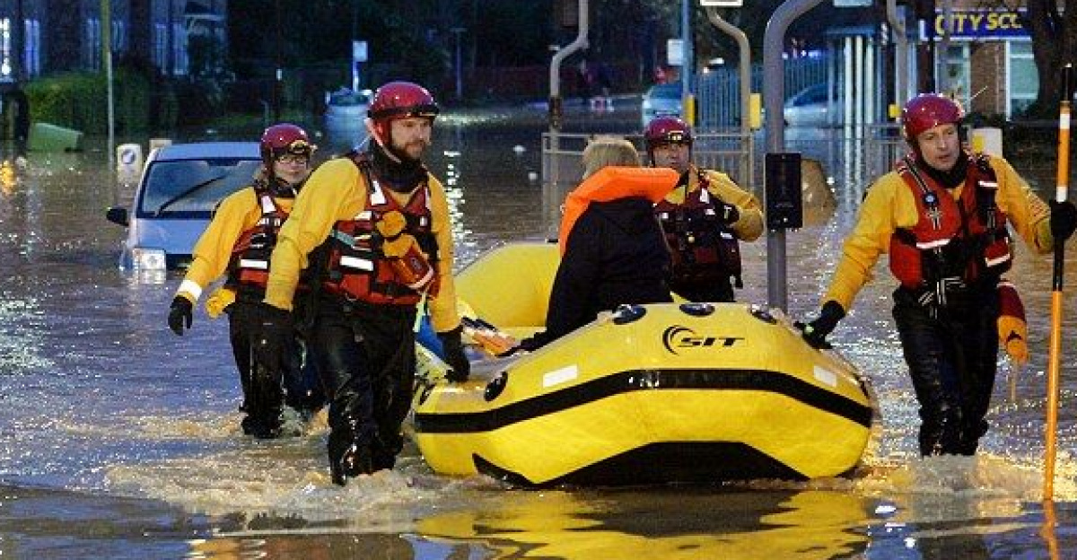 A woman is taken to safety in an inflatable boat by rescuers using rescue poles. by Reach and Rescue
