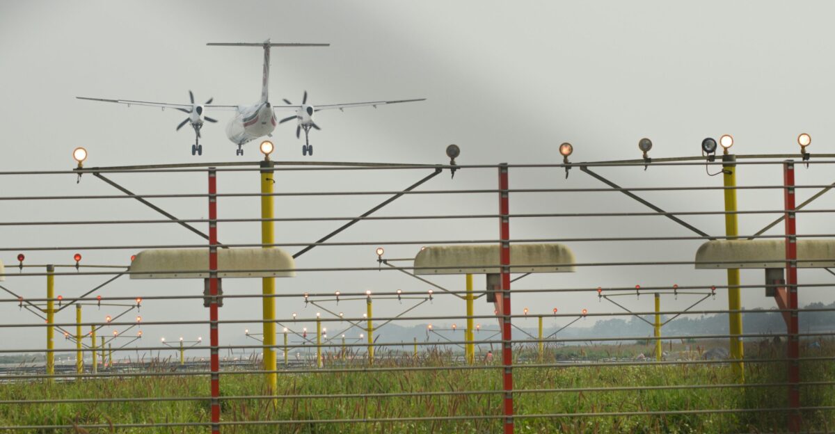 a small airplane is flying over a fence